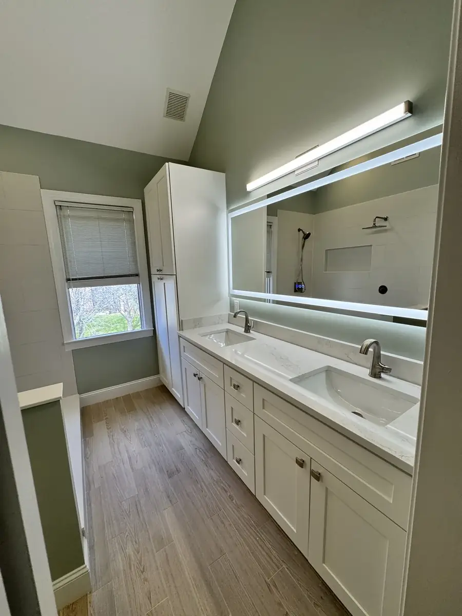 Finished bathroom with double vanity, illuminated mirror and custom storage