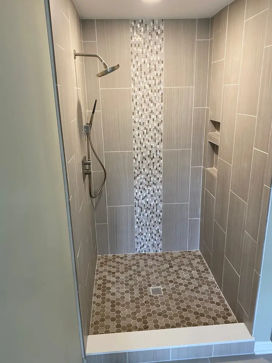 Walk-in shower finished with neutral tile and an accent band