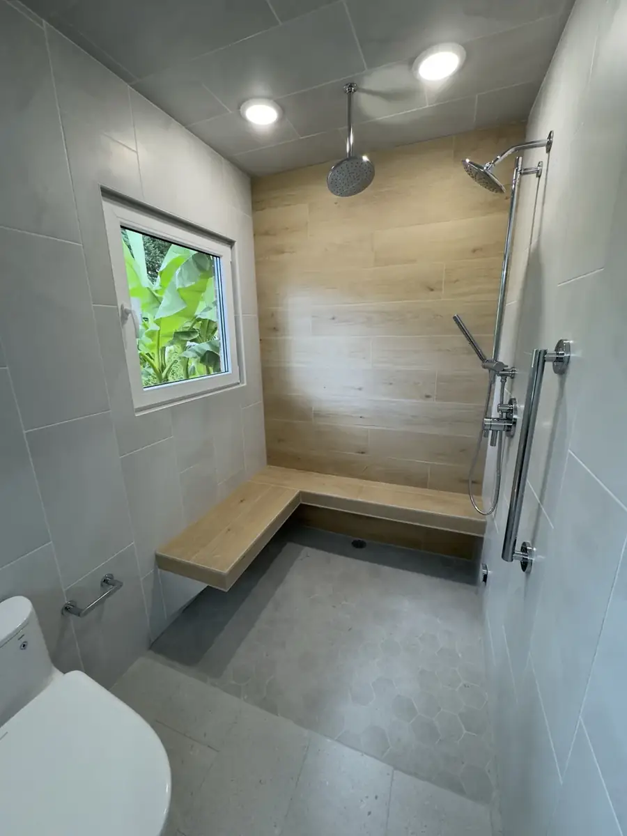 Large walk-in tile shower with built-in bench, dual shower heads and window