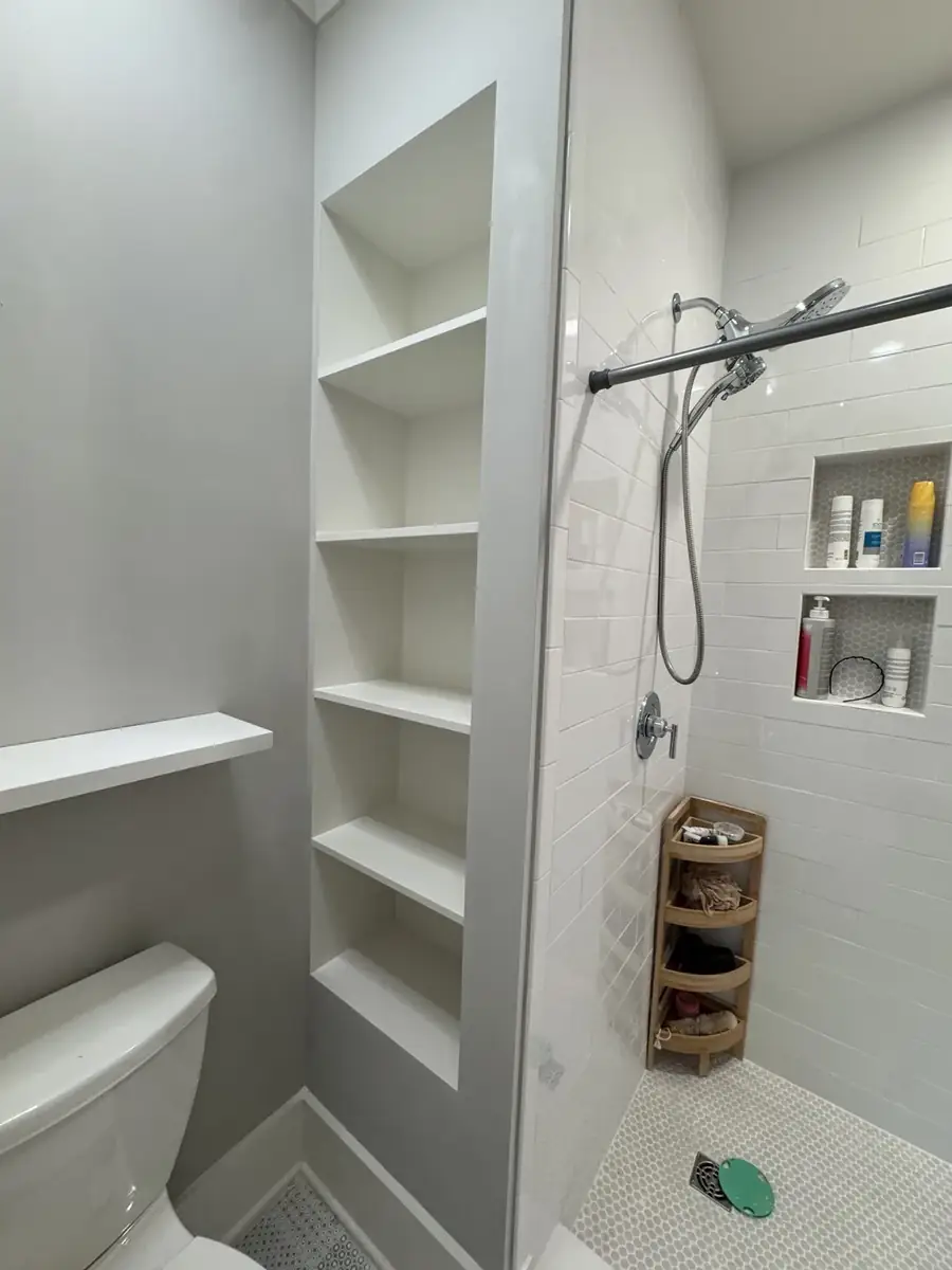 White tile shower with four built-in storage niches and penny mosaic floor