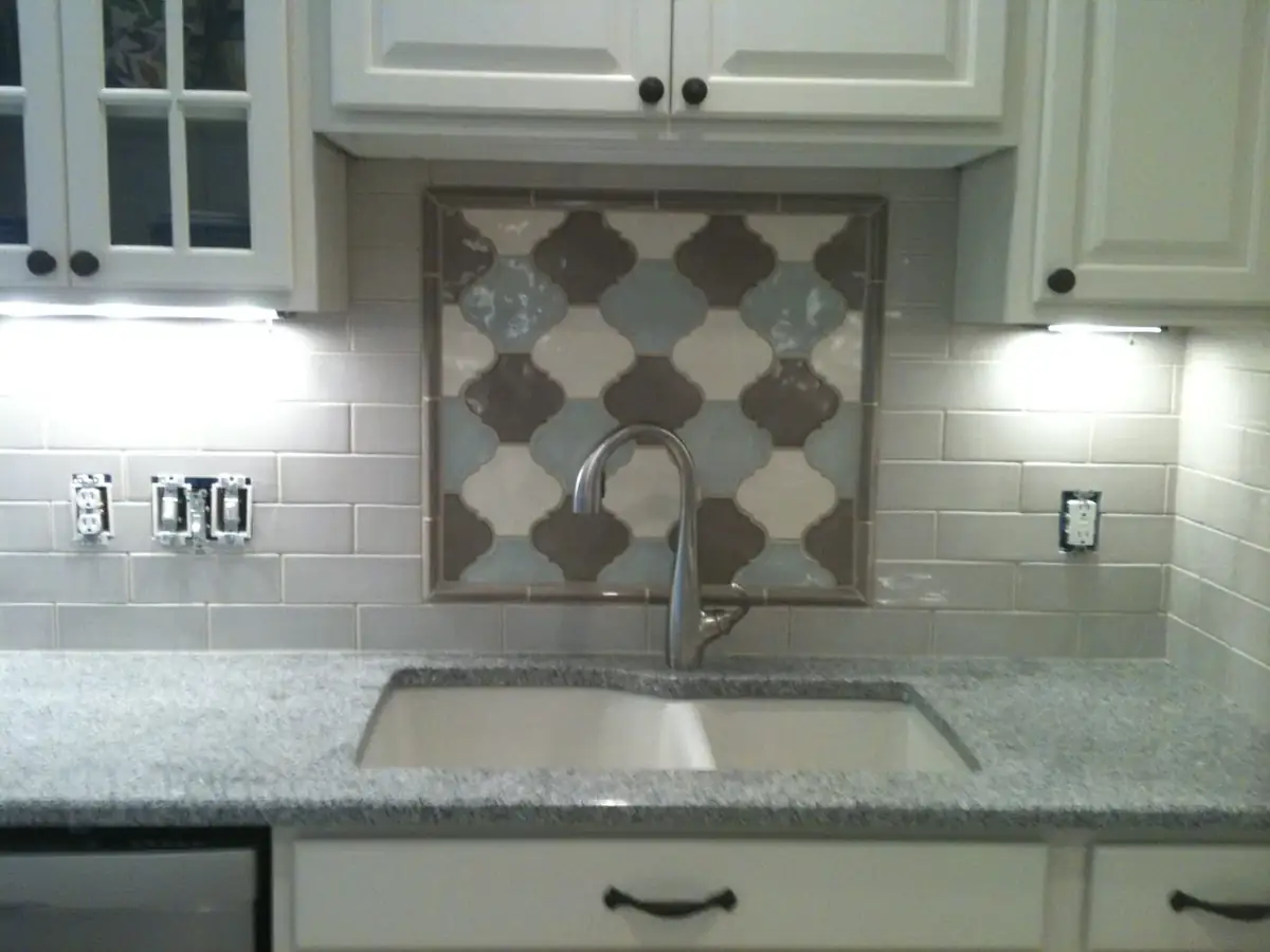 Kitchen sink wall with white cabinetry and custom tile backsplash