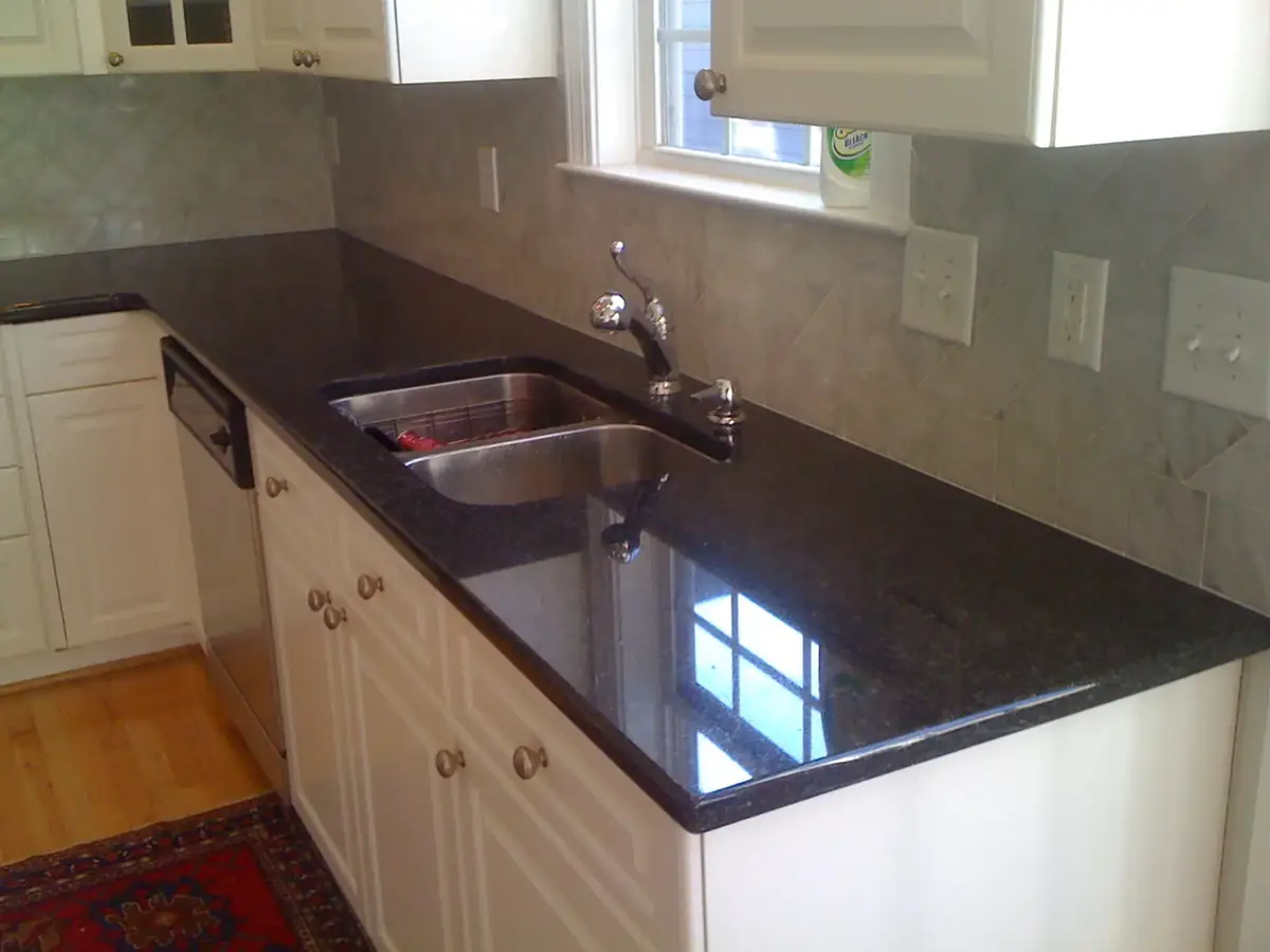 Finished kitchen with dark countertops, double sink and white cabinets