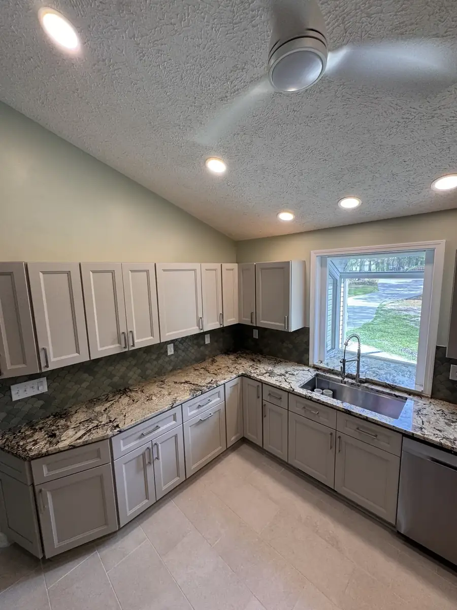 Finished kitchen remodel with light cabinetry, granite counters and custom backsplash